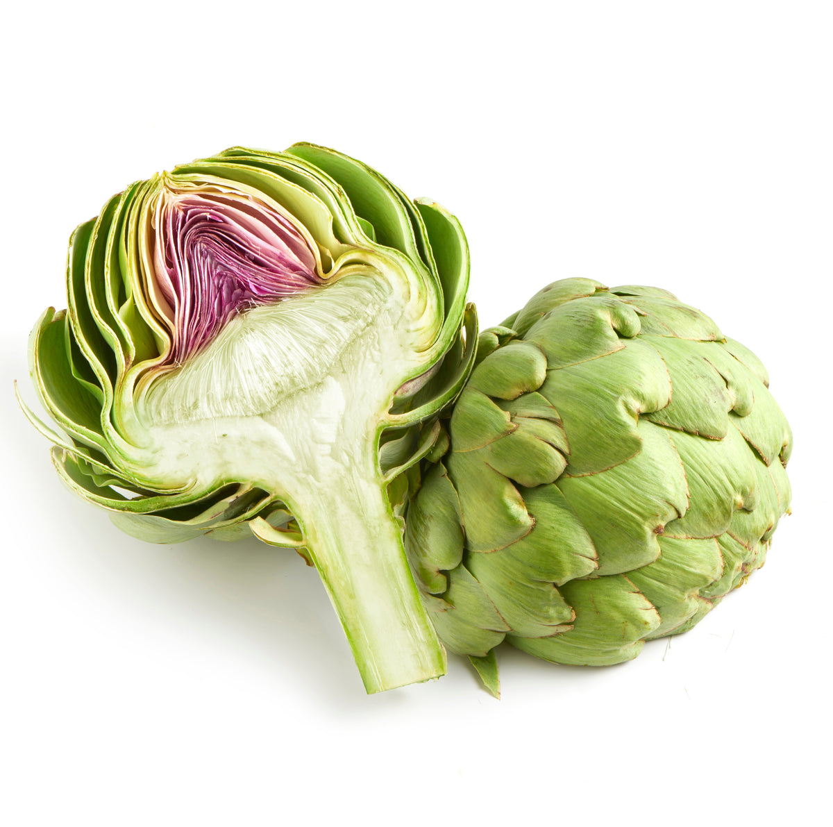 Artichoke cut in half next to a whole artichoke on a white background.