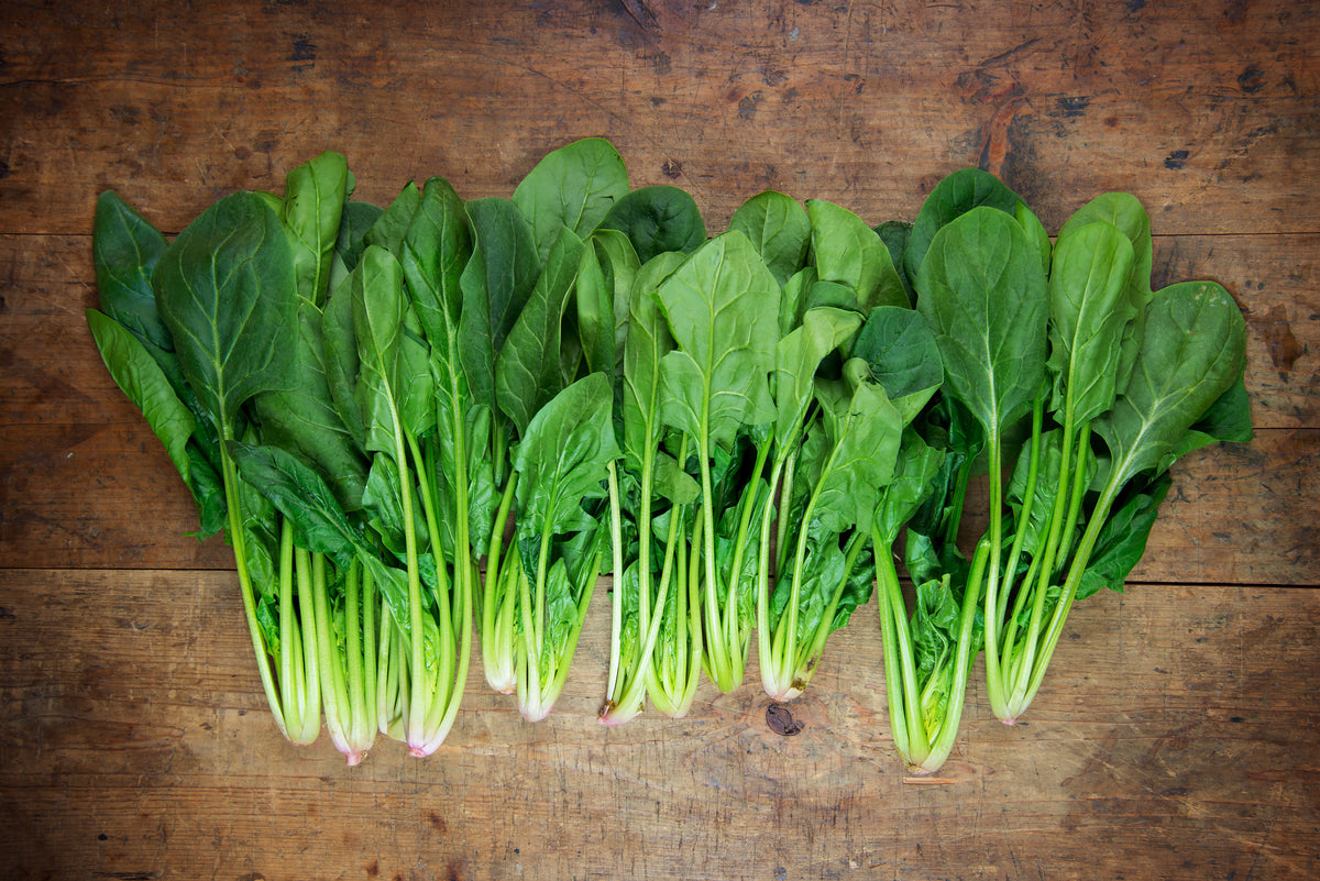 Array of bunches of baby spinach on a rustic wooden table.