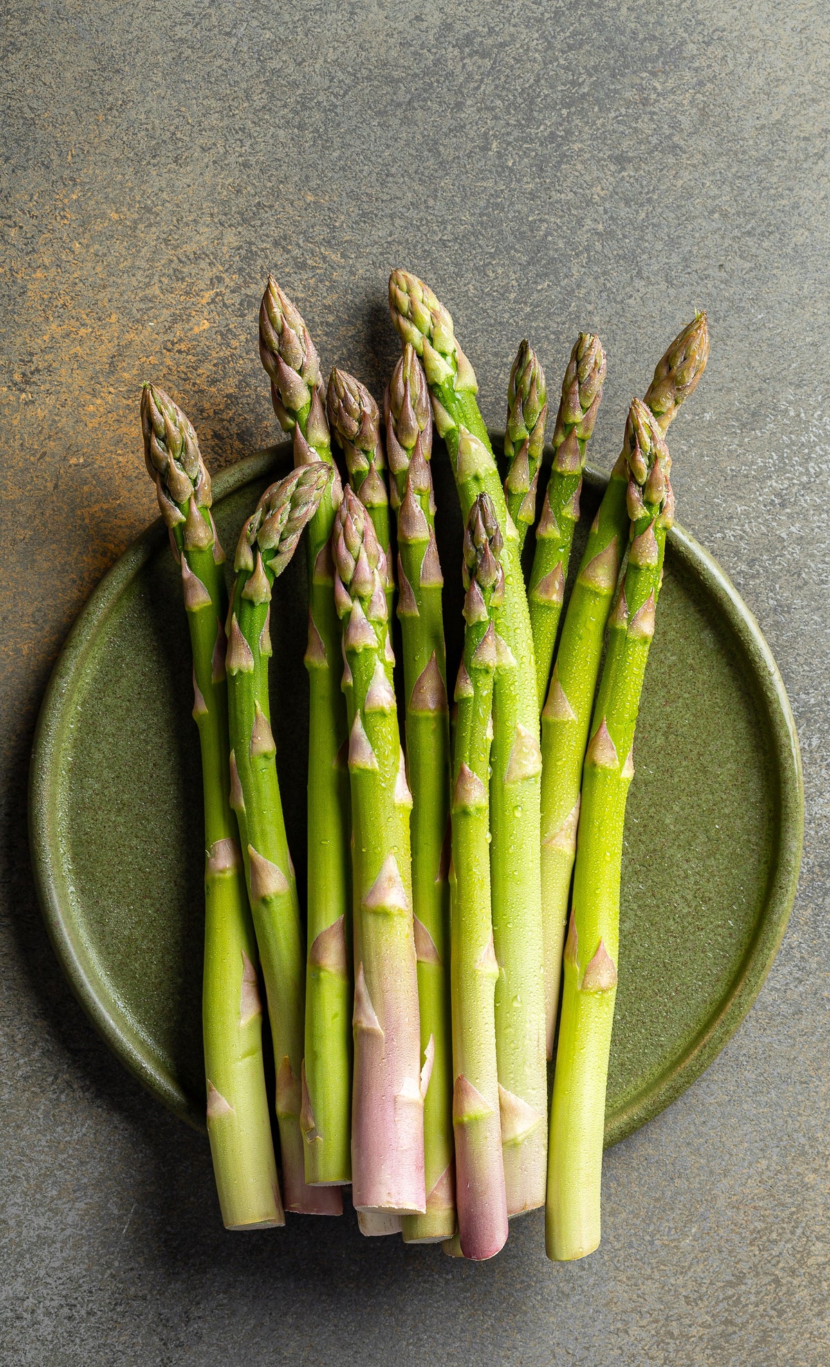 Fresh Asparagus on a plate on a kitchen counter.