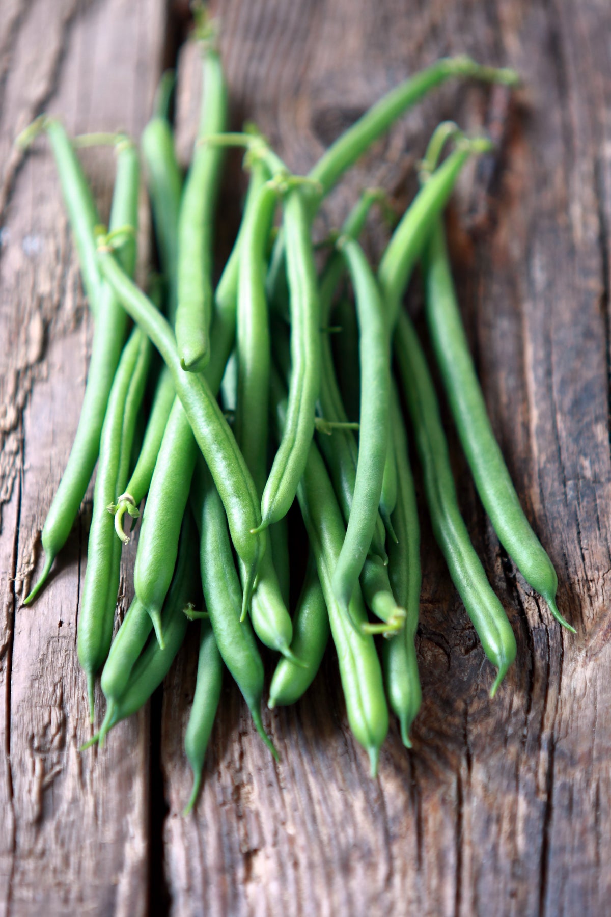 Green beans on a rustic wooden table.