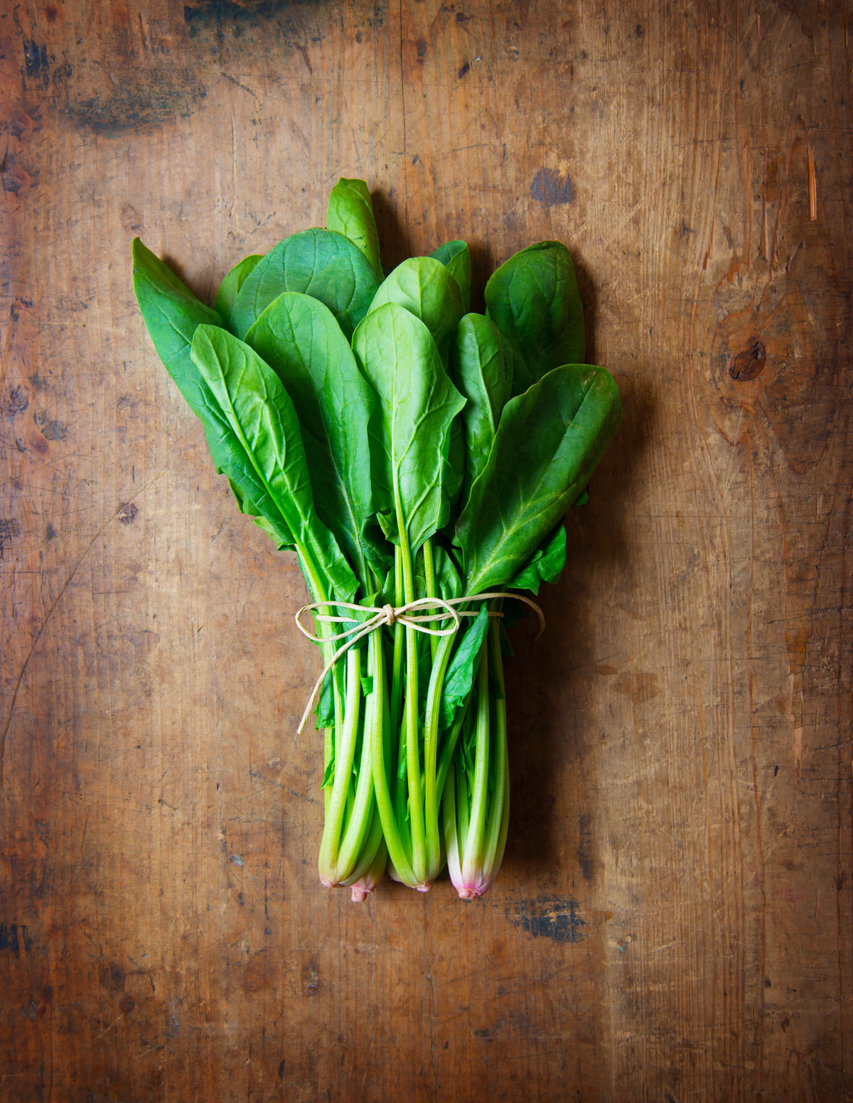 Bunched Baby Spinach on rustic wooden table.