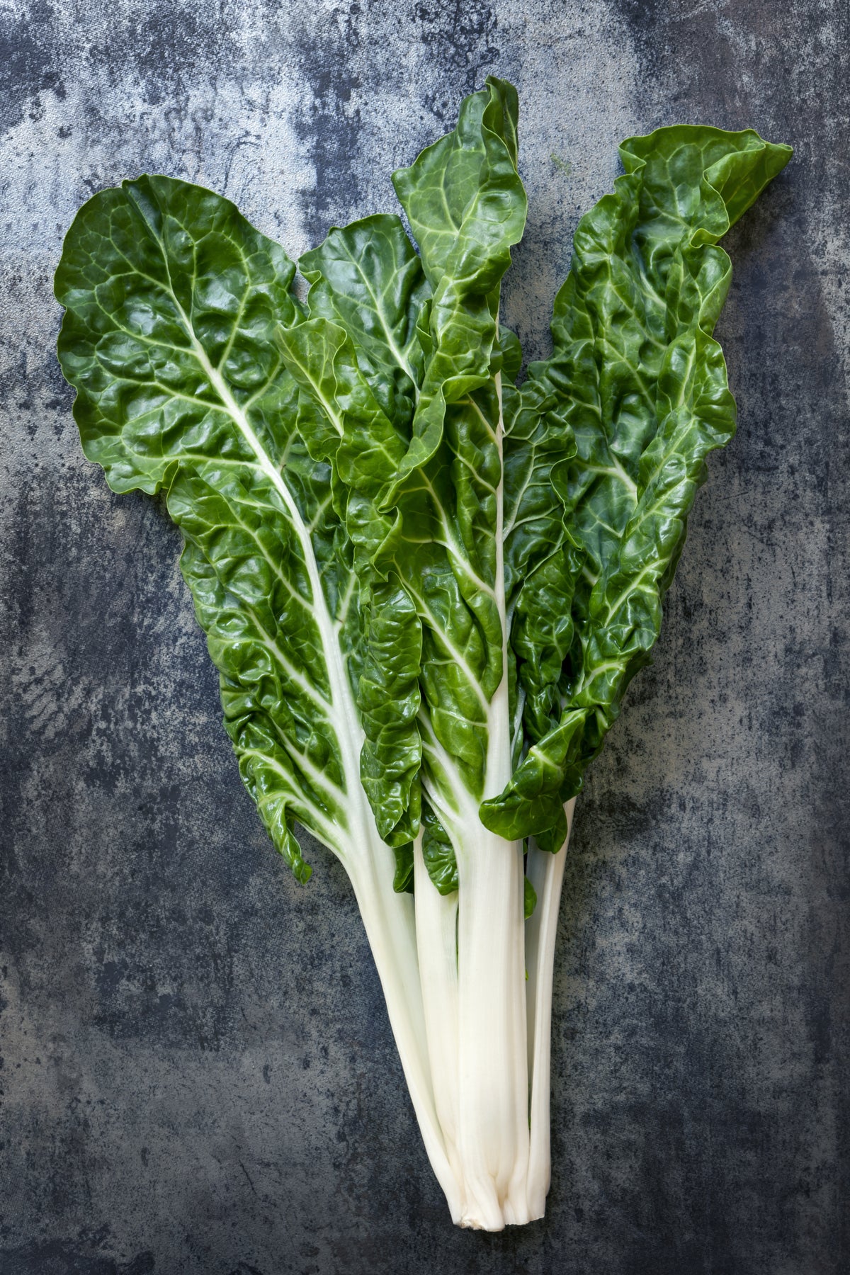 Fresh bunch of swiss chard on rustic wooden table.