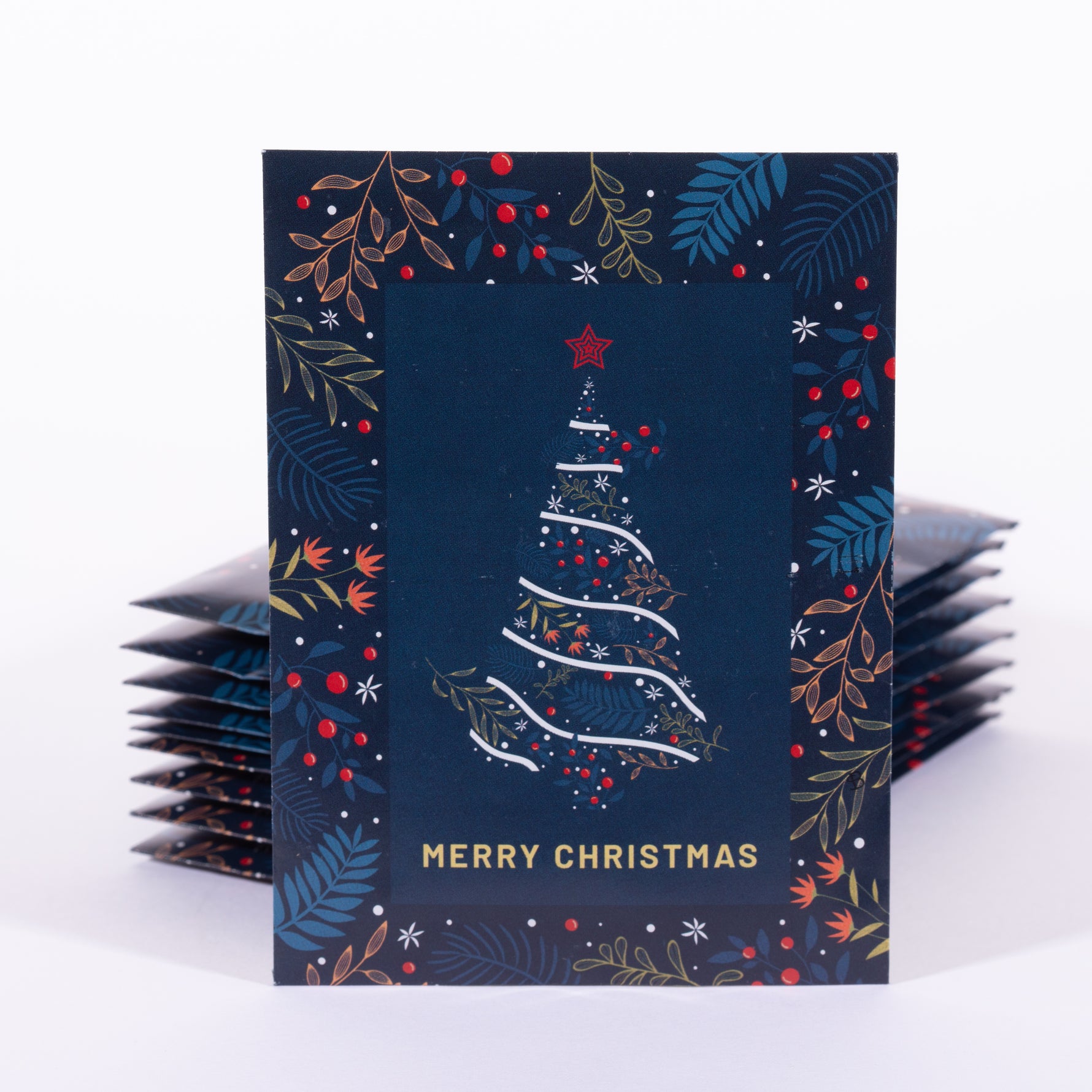 Stack of Christmas card seed packets with a decorative tree design on a dark blue background