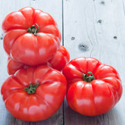Four Beefsteak Tomatoes on a wooden table. 