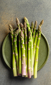 Fresh Asparagus on a plate on a kitchen counter.