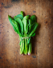 Bunched Baby Spinach on rustic wooden table.