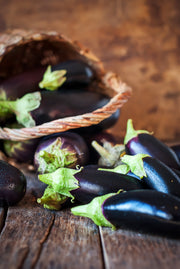 Harvest of eggplants in a basket on a rustic wooden table.
